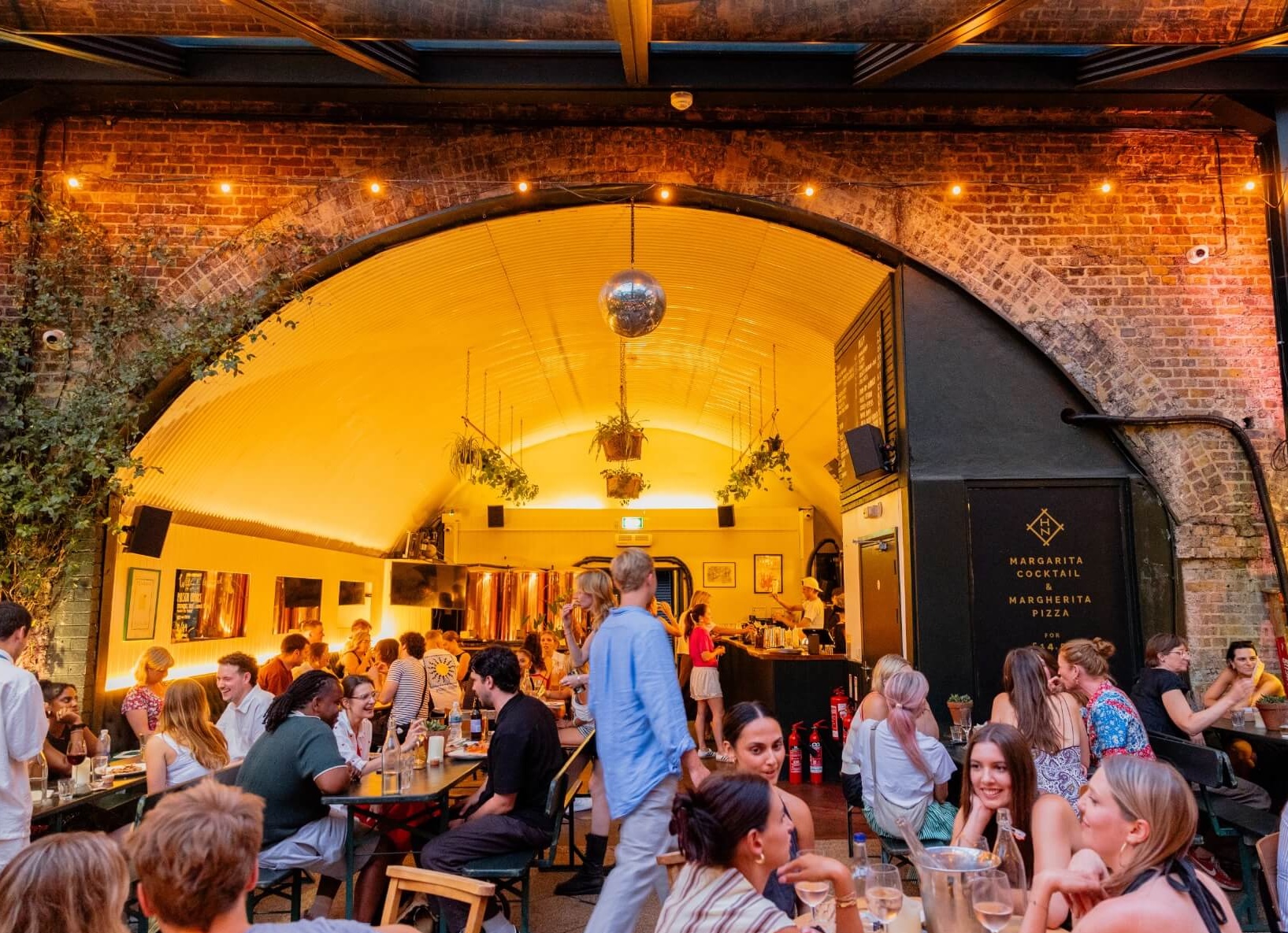 A well lit image of the bar under the arch with lots of guests drinking and eating